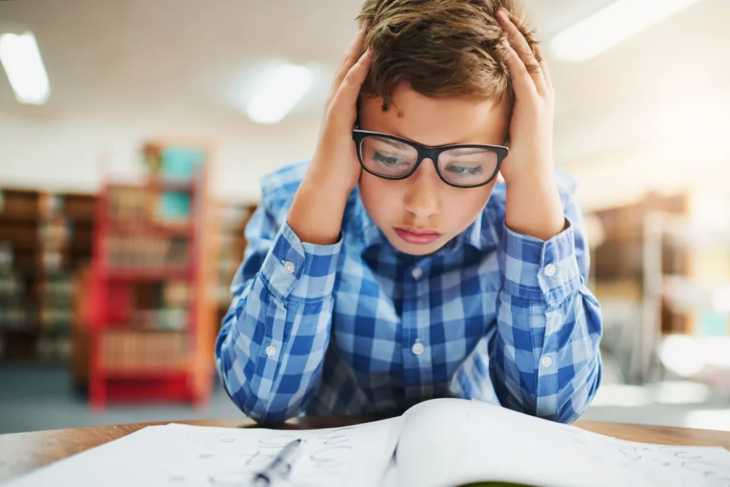 Ein junger Schüler in Brille und Hemd schaut traurig nach unten.